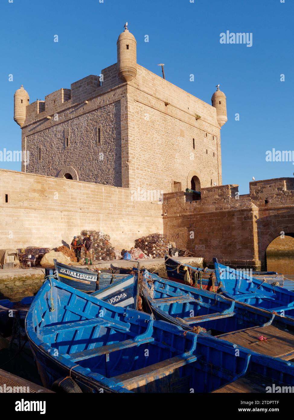 Blaue Fischerboote und Fischernetze am Turm am Fischerhafen in Essaouira, Marokko. Dezember 2023 Stockfoto