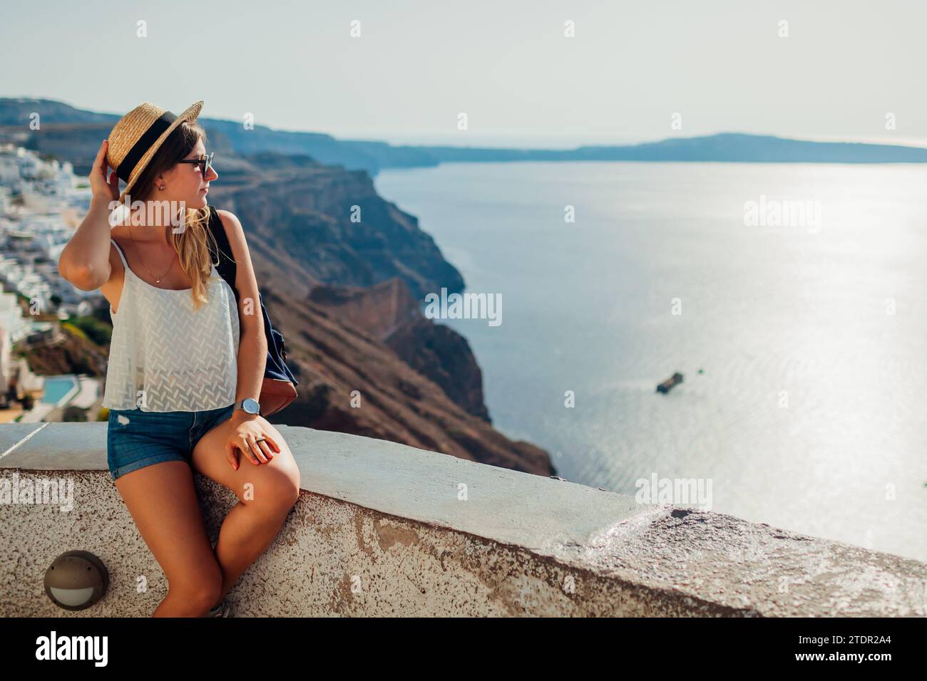 Frau, die die Caldera-Meereslandschaft in Fira, Insel Santorin genießt, mit Blick auf das Meer und die Berge. Reisen Sie während der Sommerferien Stockfoto Frau, die die Caldera-Meereslandschaft in Fira, Insel Santorin genießt, mit Blick auf das Meer und die Berge. Reisen Sie während der Sommerferien Stockfoto