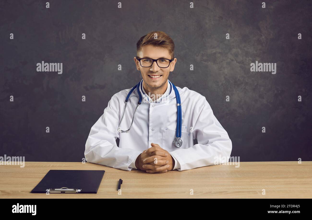 Portrait of confident and friendly smiling male doctor on gray concrete background. Stockfoto