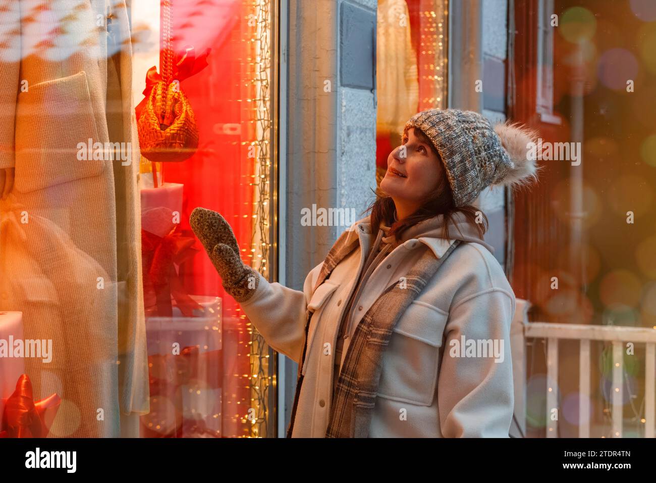 Eine lächelnde Frau in ihrer Blüte, die den Charme einer nordischen Stadt, die zu Weihnachten und Neujahr dekoriert ist, bewundert. Hochwertige Fotos Stockfoto