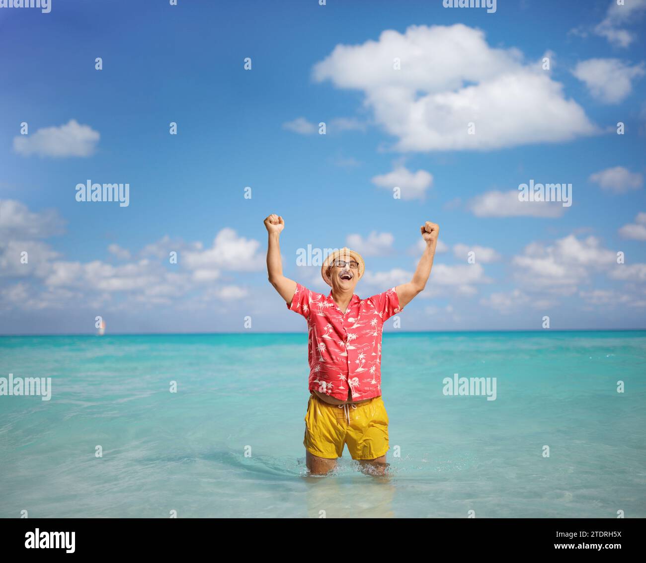 Überglückter reifer Mann in einem Sommerurlaub, der Glück mit den Armen hoch im Meer gestreckt hat Stockfoto