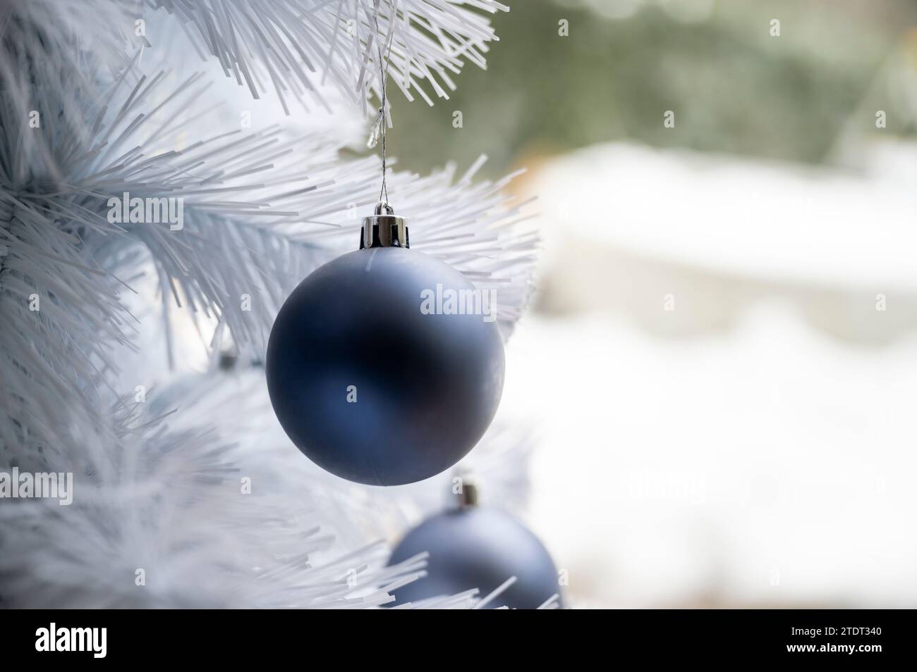 Nahansicht der blauen weihnachtskugel, die an einem weißen Weihnachtsbaum hängt. Stockfoto