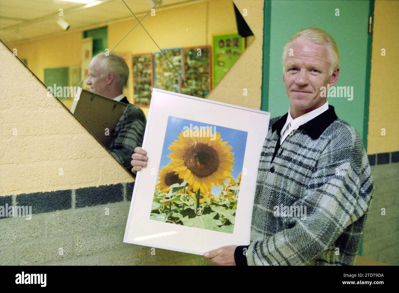 Mann mit Sonnenblumenmalerei neben einem Spiegel, Whizgle News aus der Vergangenheit, zugeschnitten auf die Zukunft. Erkunden Sie historische Geschichten, das Image der niederländischen Agentur aus einer modernen Perspektive, die die Lücke zwischen den Ereignissen von gestern und den Erkenntnissen von morgen überbrückt. Eine zeitlose Reise, die die Geschichten prägt, die unsere Zukunft prägen Stockfoto