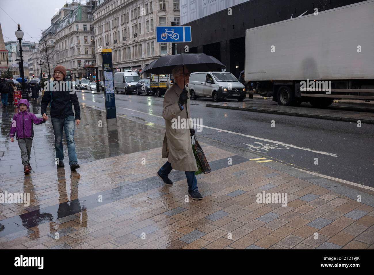 Mann in Regenmantelunterkünften unter seinem Regenschirm an einem nassen Wintertag, London, England, Großbritannien Stockfoto