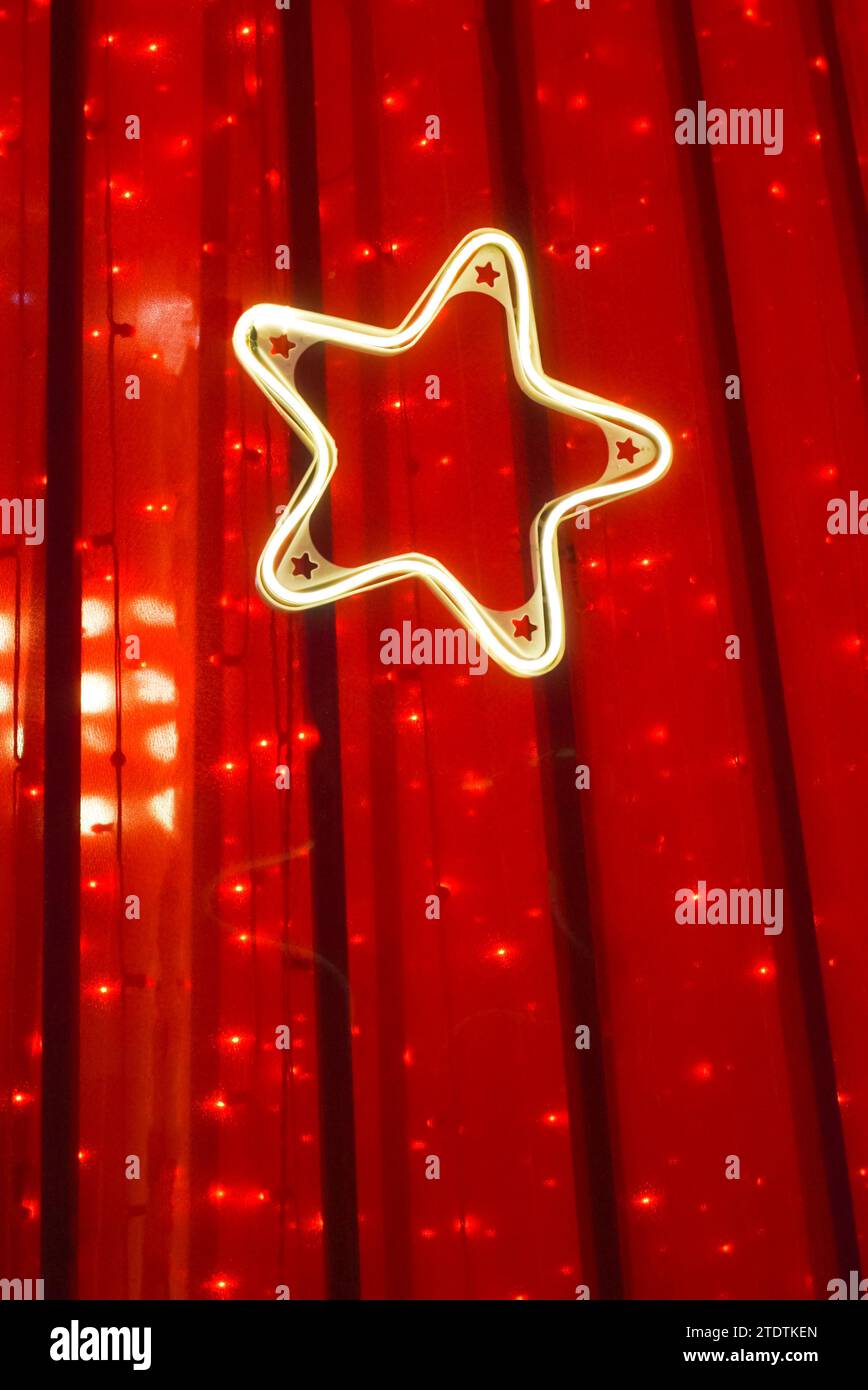 Nahaufnahme eines Lichtsterns auf rotem Vorhang. Hintergrund für Veranstaltungsdekoration. Stern. Kopierbereich. Stockfoto