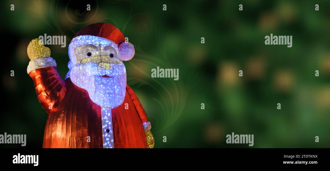 Nahaufnahme einer Santa-Klausel auf grünem Bokeh-Hintergrund mit Blumenwirbel. Weihnachtsgruß. Kopierbereich. Stockfoto