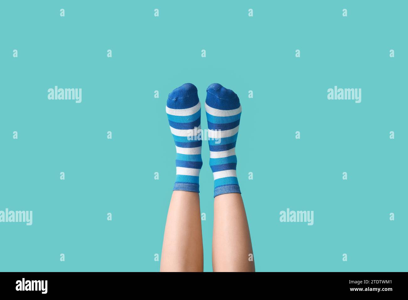 Beine einer jungen Frau in gestreiften Socken auf blauem Hintergrund Stockfoto