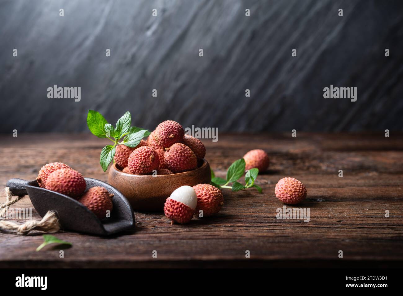 Schüssel mit Reifen tropischen Flechtenfrüchten (Litchi chinensis) auf hölzernem Hintergrund Stockfoto