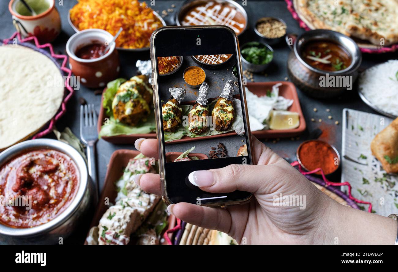 Hände eines Bloggers, der ein Foto von indischem Essen macht, um es in sozialen Netzwerken zu teilen Stockfoto