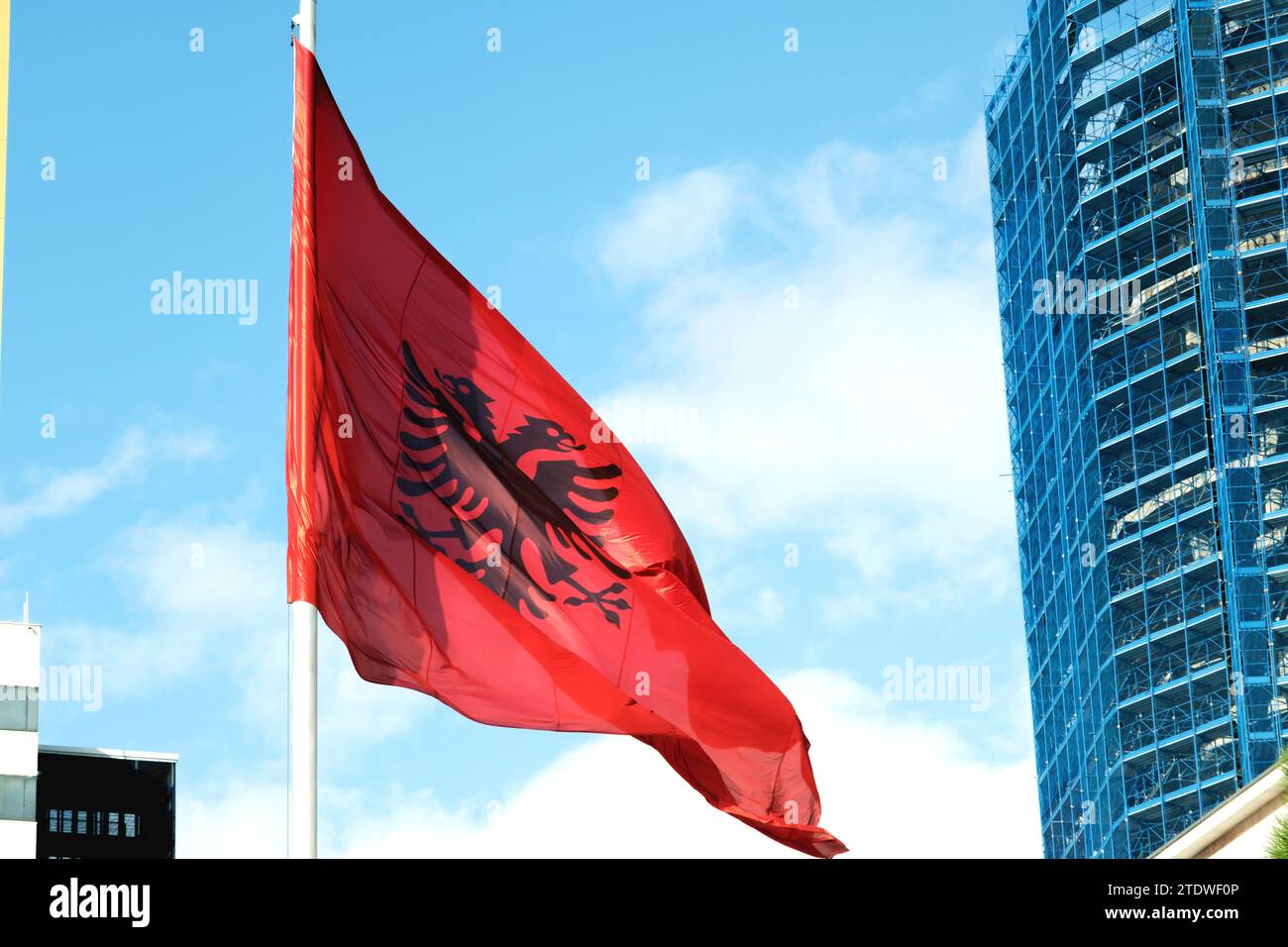 Große albanische Flagge flattert im Wind vor einem klaren blauen Himmel und symbolisiert nationalen Stolz und Erbe Stockfoto