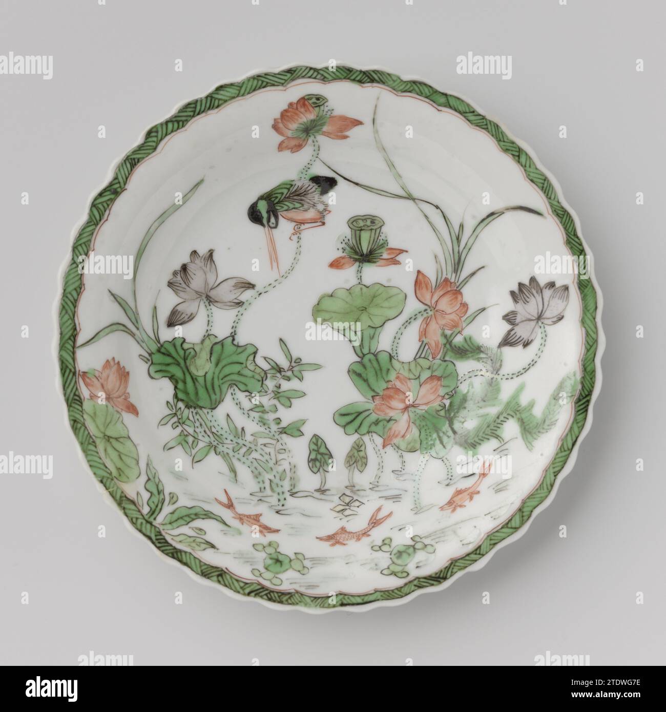 Untertasse mit Teich, Lotuspflanzen, Fische und Vögel, anonym, ca. 1700 - ca. 1724 Untertasse aus Porzellan mit gelapptem Rand, in Unterglasur blau bemalt und auf der Glasur rot, grün, gelb, Auberginen und schwarz. Auf der Ebene der Schüssel ein Teich mit Lotuspflanzen, drei Fischen und einem eisvogel, der Rand mit Zickzackarbeit; drei Blütenzweige auf der Rückseite. Die Schale ist auf dem Boden mit einer Dichtungsmarke in einem Doppelkreis gekennzeichnet. Famle Verte. Porzellan. Glasur. Kobalt-(Mineral-)Malerei / Glasur Porzellanuntertasse mit gelapptem Rand, lackiert in unterschwelliger Glasur blau und auf der Glasur rot, grün, gelb, Aubergine und bl Stockfoto