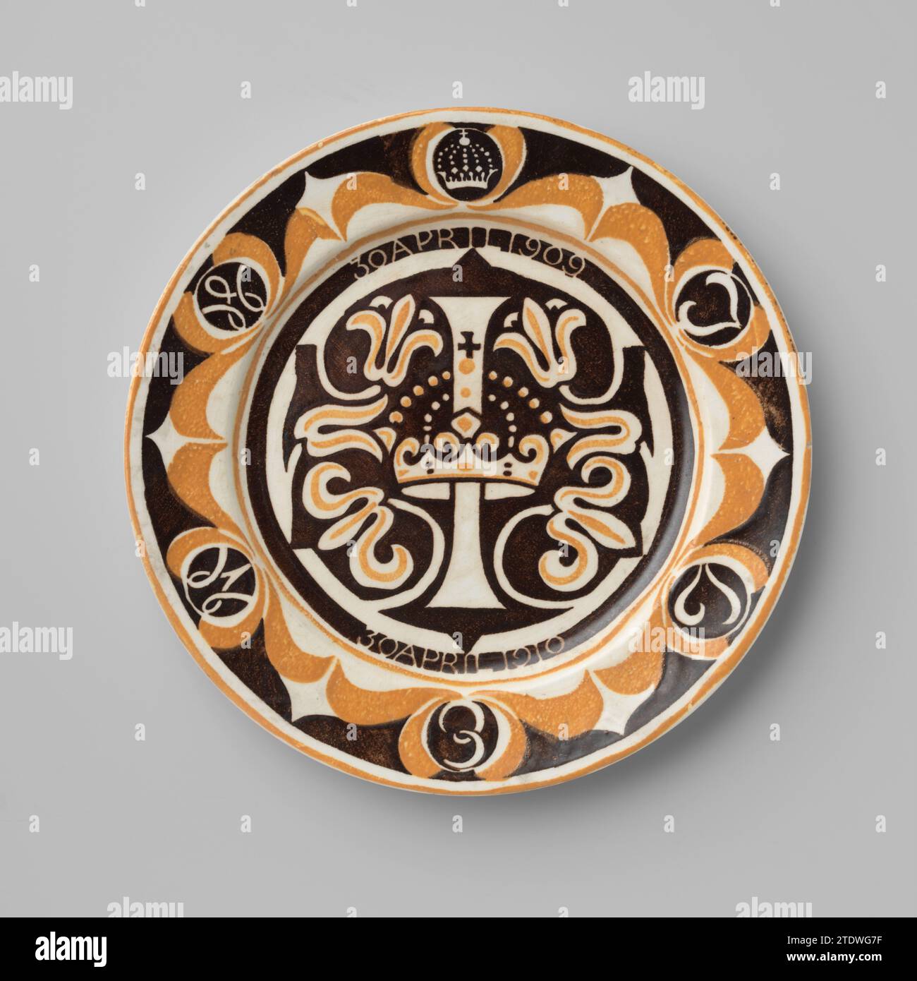 Gedenktafel für die einjährige Prinzessin Juliana, Carel Adolph Lion Cachet, 1910 Gemenkbrett aus Steingut, hergestellt anlässlich des ersten Geburtstags von Prinzessin Juliana, mit einem bedruckten Hintergrund in Gelb und Mangan. In der Mitte der Buchstabe I, erstochen von einer Krone, um die Blumenhäute, in einem Manganstock gerettet. Oberhalb der I 30 April 1909, unterhalb der I 30 April 1910, gerettet in einem breiten Manganbies. Am Rand oben auf einer Krone, dann im Uhrzeigersinn entlang der Buchstaben J, L, E, M und W, gespeichert in einem Mangan-Medaillon innerhalb einer gelben Blüte Herausforderung. Eine gelbe Rohrleitung entlang der Kante. Stockfoto