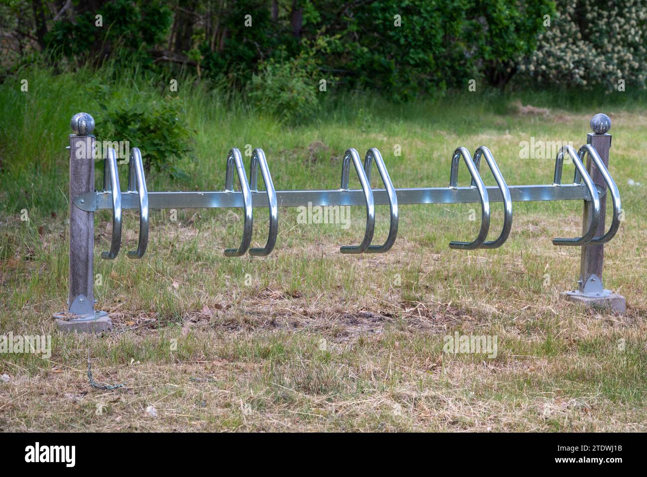 Radträger aus grauen Blechrohren in Form eines Rechtecks auf dem Rasen, Pflaster aus Granitwürfeln in der Stadt, Schotter, Parkweg Stockfoto