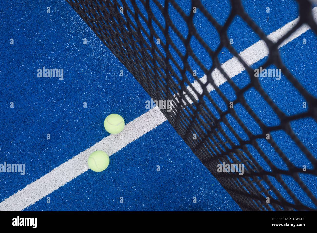 Zwei Bälle in der Nähe des Netzes in einem blauen Paddle-Tennisplatz mit Blick von oben Stockfoto