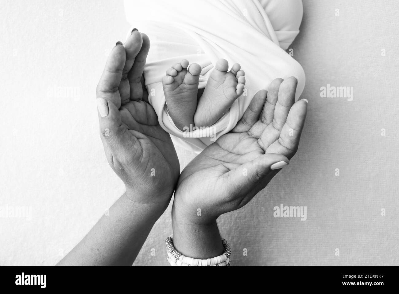 Die Handflächen der Eltern, Vater und Mutter halten die Beine, Füße des Neugeborenen Stockfoto