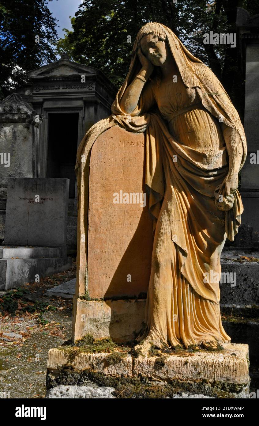 Eine sonnendurchflutete Skulptur steht an einem Grab auf dem historischen Pariser Friedhof Père Lachaise. Stockfoto