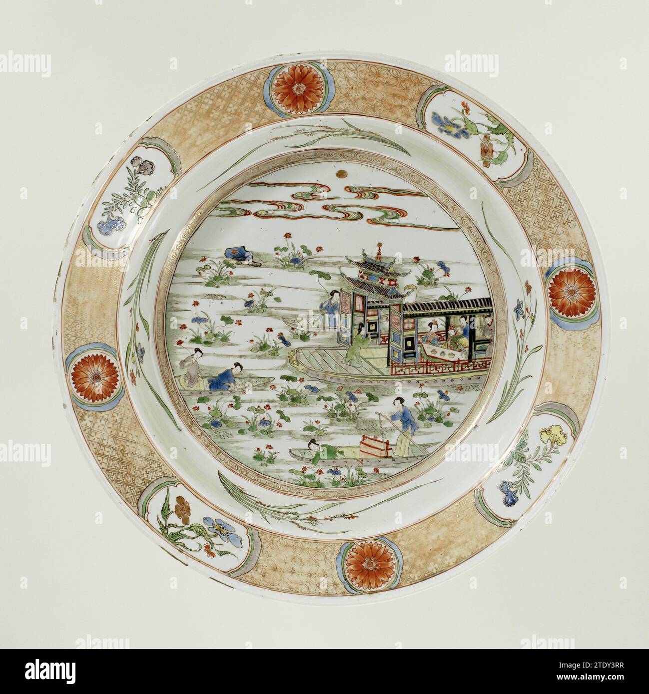 Becken mit mehreren Booten auf einem Fluss gefüllt mit Lotuspflanzen, anonym, ca. 1700 - ca. 1724 Tiefe Porzellanschale, auf der Glasur in blau, rot, grün, gelb, Aubergine gemalt, schwarz und Gold. In der Wohnung ein Boot auf einem Fluss voller Lotuspflanzen, mit einem Mann und einer Frau an einem Tisch, umgeben von drei Dienern; drei kleine Boote fahren um das große Boot, von denen jedes zwei Mägde Lotuspflanzen pflücken; zu zeigen ist eine Band mit Lockenarbeit; vier blühende Orchideen an der Wand; der Rand mit Servierwerk in Gold auf rotem Boden mit abwechselnd einer Blumenrosette und vier Kartuschen mit einer blühenden pla Stockfoto