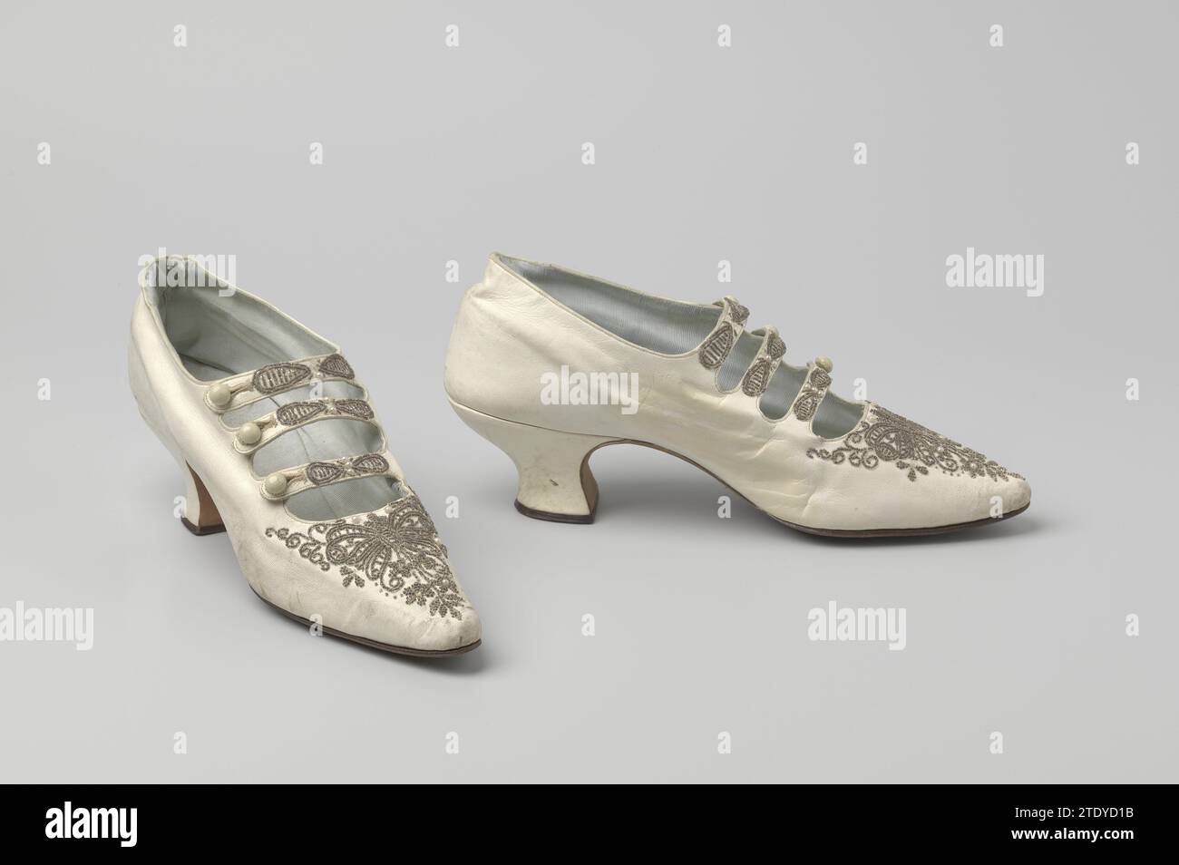 Bandschuh aus weißem Glacé-Leder mit drei Riemen mit weißem konvexem Knoten, verziert mit weißen Glasperlen und Perlen, ca. 1895 - ca. 1905 Bandschuh aus weißem Glacé-Leder mit weißen Glasperlen und Edelsteinen. Schuhe mit drei Riemen und weißen konvexen Knöpfen. Sehr spitz zulaufende Nase, niedrige Pompadour-Absätze. Futter aus hellblauem Riss an der Seite. Brüssel (möglicherweise) .. Seidenbandschuh aus weißem Glacé-Leder mit weißen Glasperlen und Edelsteinen. Schuhe mit drei Riemen und weißen konvexen Knöpfen. Sehr spitz zulaufende Nase, niedrige Pompadour-Absätze. Futter aus hellblauem Riss an der Seite. Brüssel (möglicherweise) .. Seide Stockfoto