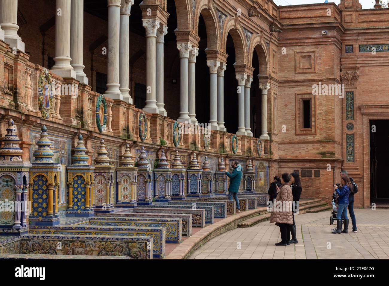 Menschen, Besucher, die Azulejos-Alkoven auf der Plaza de España in Sevilla oder Sevilla, Spanien oder España, Europa, schätzen. Aufgenommen am 6. Dezember 2023. Stockfoto