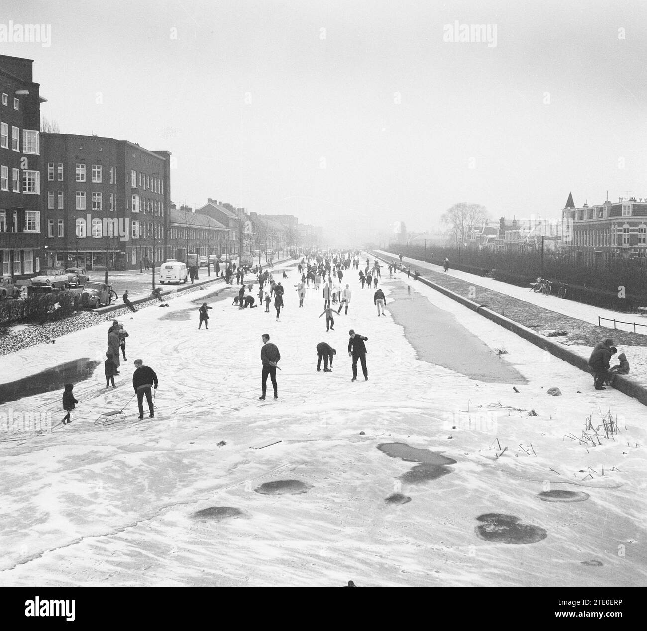 Kinder und Erwachsene, die auf einem gefrorenen Kanal oder Fluss in den Niederlanden Schlittschuhlaufen ca. Dezember 1962 Stockfoto