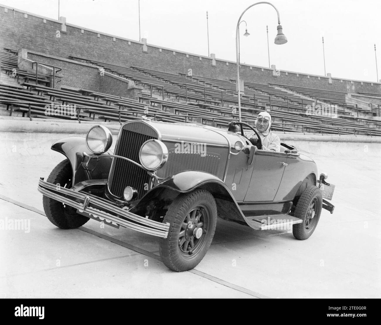 Rennfahrer Van Marle in seinem zweisitzigen Chrysler Cabriolet fährt links vor leeren Tribünen im Olympiastadion in Amsterdam Süd. CA. 1932 Stockfoto