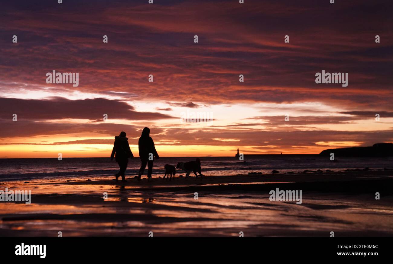 Menschen gehen mit ihren Hunden am Tynemouth Beach, Tyne and Wear, an der Nordostküste Englands. Bilddatum: Mittwoch, 20. Dezember 2023. Stockfoto