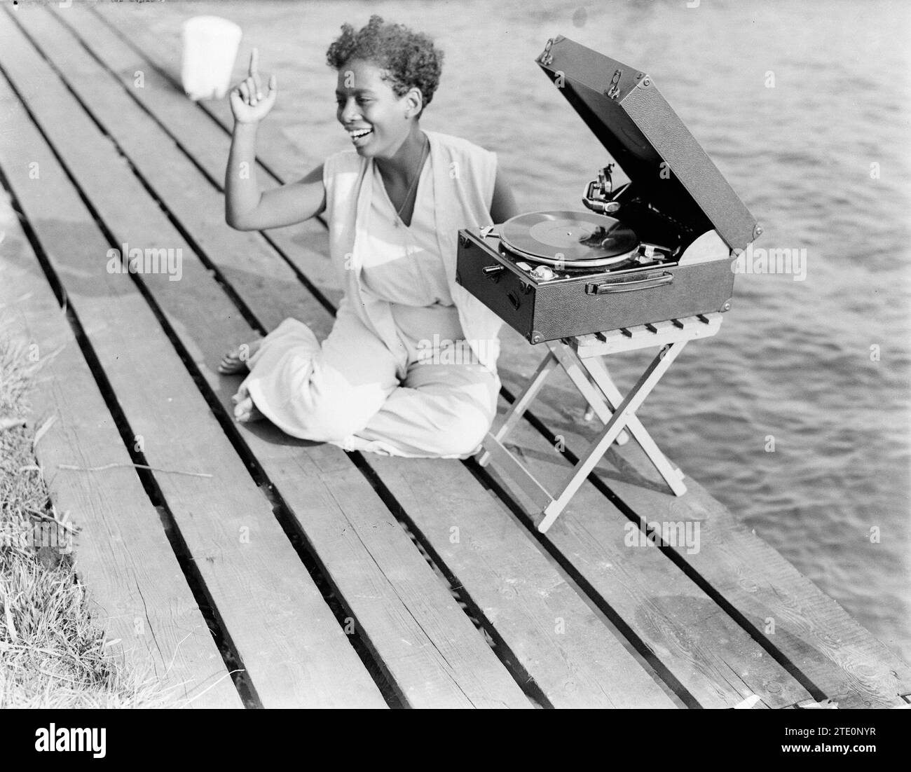 Unbekannte Frau spielt Schallplatte auf Koffer-Grammophon auf einer Anlegestelle. 1932 Stockfoto