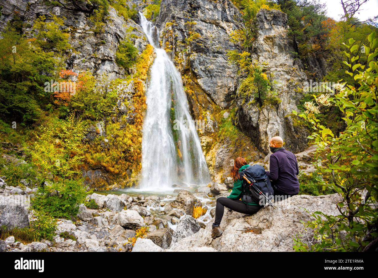Menschen, die vor dem Wasserfall in Theth, Albanien, sitzen Stockfoto