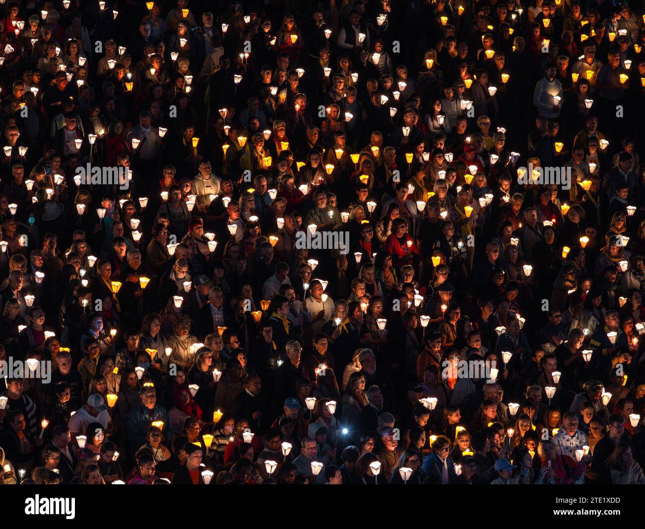 Lourdes, Frankreich - 12. Oktober 2023: Eine Pilgergruppe mit brennenden Kerzen betet bei einer nächtlichen Pilgerprozession in Lourdes. Stockfoto