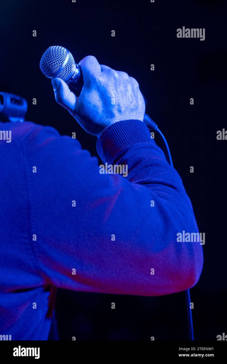 Dynamischer Sänger, der unter faszinierenden blauen Lichtern auf der Bühne auftritt. Stockfoto