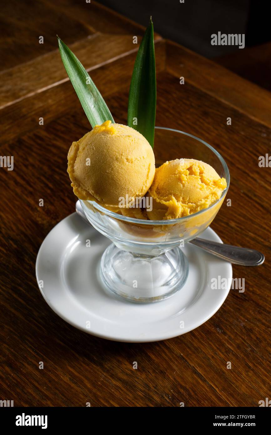 Köstliches Karamell- und Vanilleeis in einem Glas, geschmückt mit Ananasblättern. Stockfoto