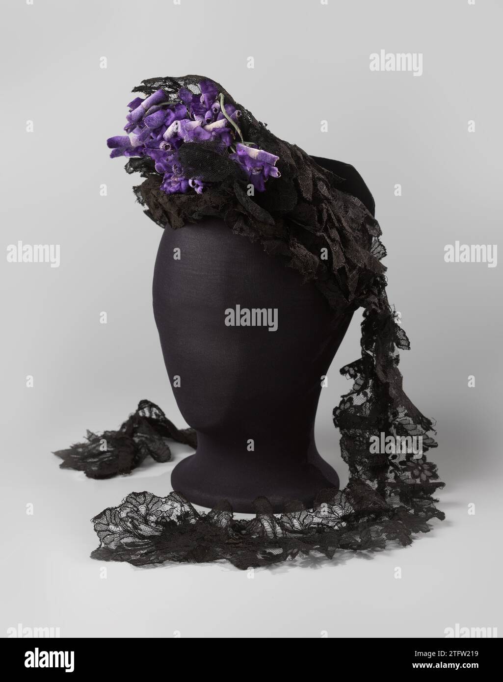 Kapitel der maschinenschwarzen chantilly-Seite und der schwarzen Blondine, anonym, um 1885 Kapitel der maschinenschwarzen chantilly-Spitze und der schwarzen Blondine, schwarzer Band aus Samt und Tüll, mit lila Blüten. Halterungsform mit Rudiment aus einer Haube für den Kopf. Die Seite ist zerknittert und auf einer U-förmigen Laiton-Halterung gefaltet, die mit schwarzem Samtbesatz bedeckt ist. Rant-Streifen in Diademform hinter einem großen Schuss samtvioletter Blüten. In der Öffnung für den Chignon eine kurze Schleife aus Bandsamt. An der Spitze mit Hut und Rutsch verlängert, gleichzeitig Kehlreifen. Niederlande (möglicherweise) ganz:. Ganz:. Ganz Stockfoto
