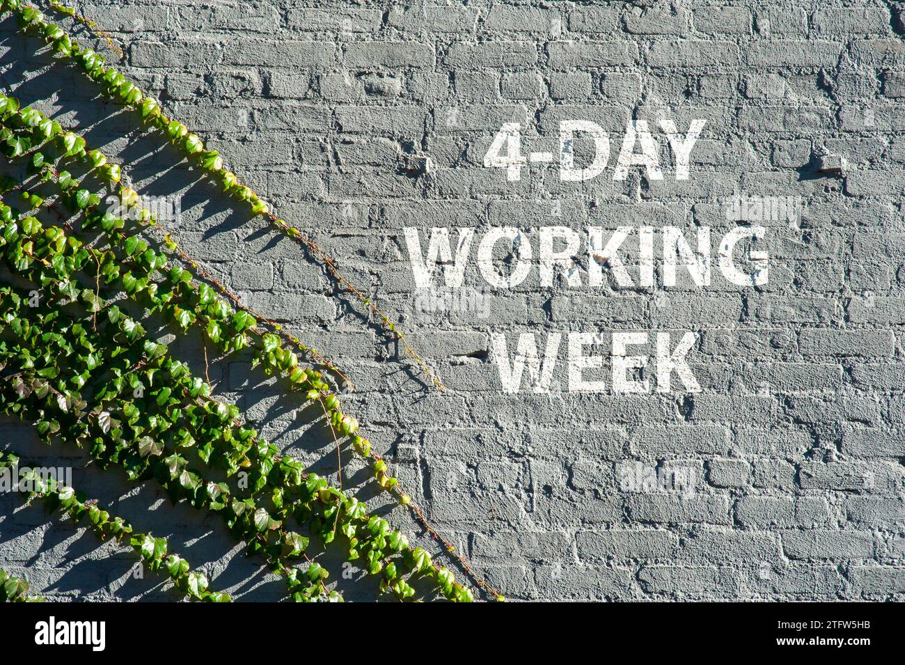 4 - Tagesarbeitswoche auf einer Backsteinmauer mit grünen Blättern, die die Natur symbolisieren, die das städtische Leben übernimmt. Stockfoto