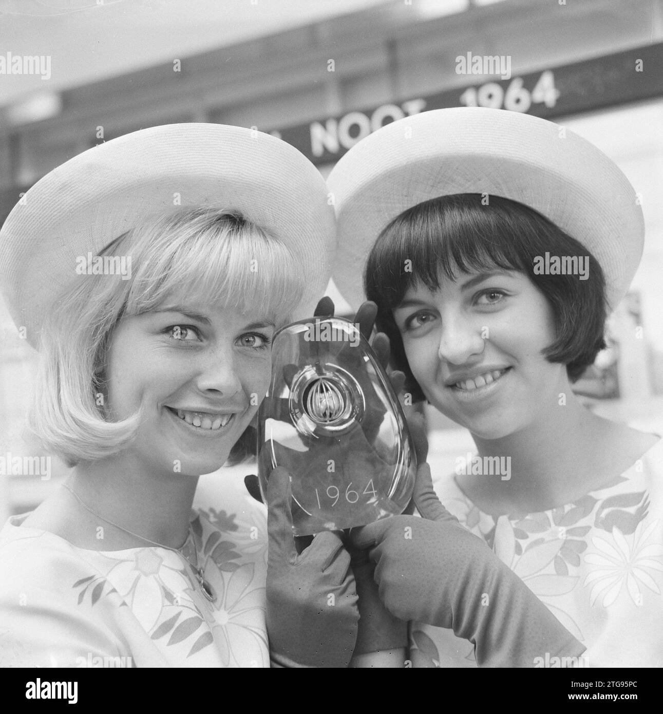 Verpackungsinnovationswettbewerb de Gouden Noot – zwei Blumenmädchen zeigen den Golden Nut Award oder den Golden Walnut Award ca. April 1964 Stockfoto