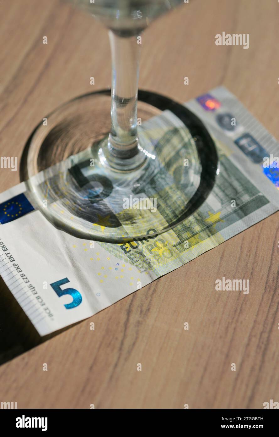 Fünf-Euro-Geldschein unter einem Stielglas. Stockfoto