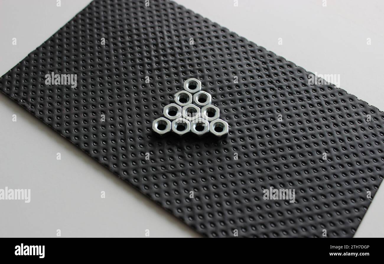 Stahlmuttern In Form Von Play-Tasten Auf Schwarzer Gummierter Platte Stockfoto