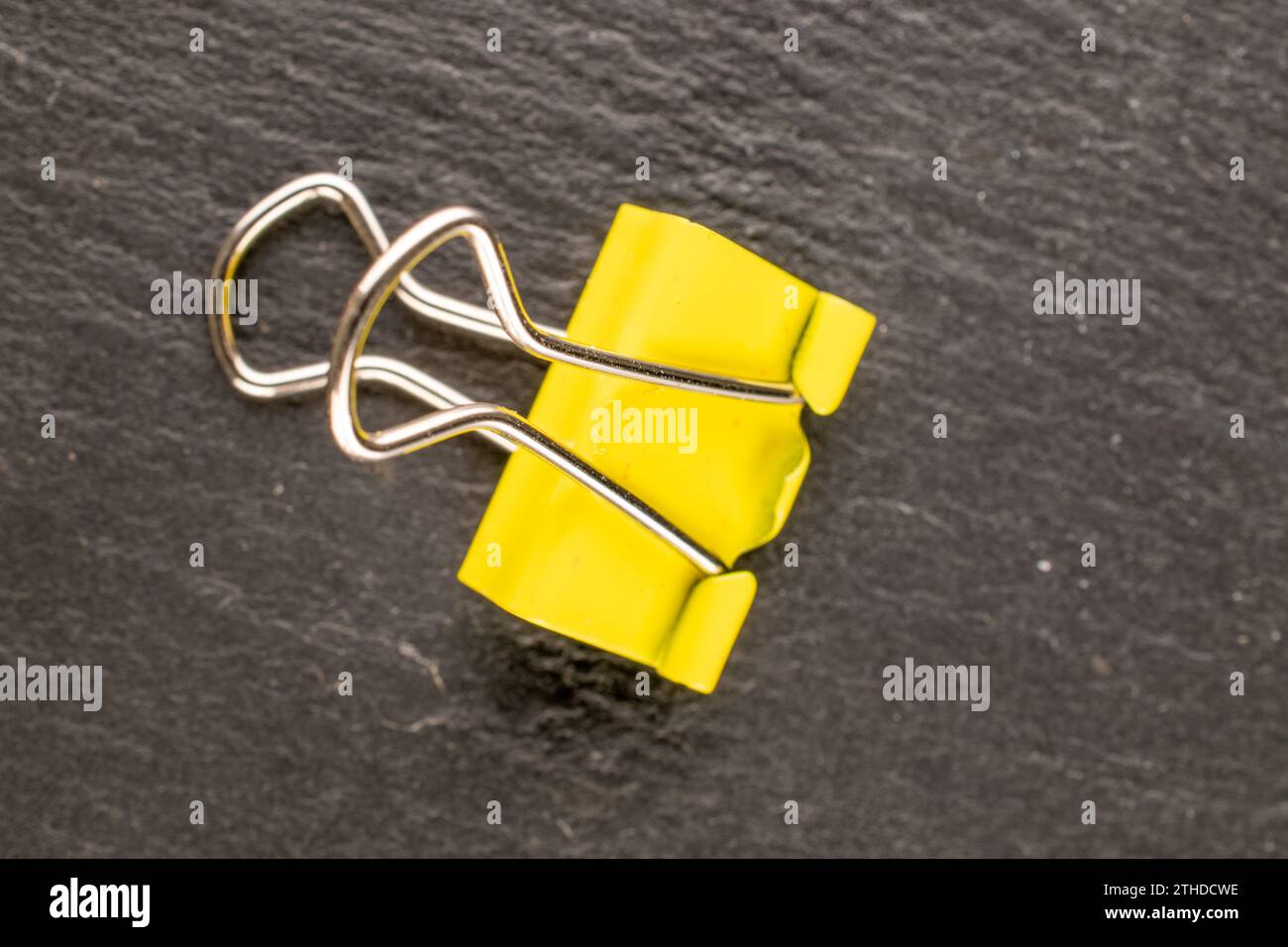Eine Büroklammer aus Metall auf Schieferstein, Makro, Draufsicht. Stockfoto