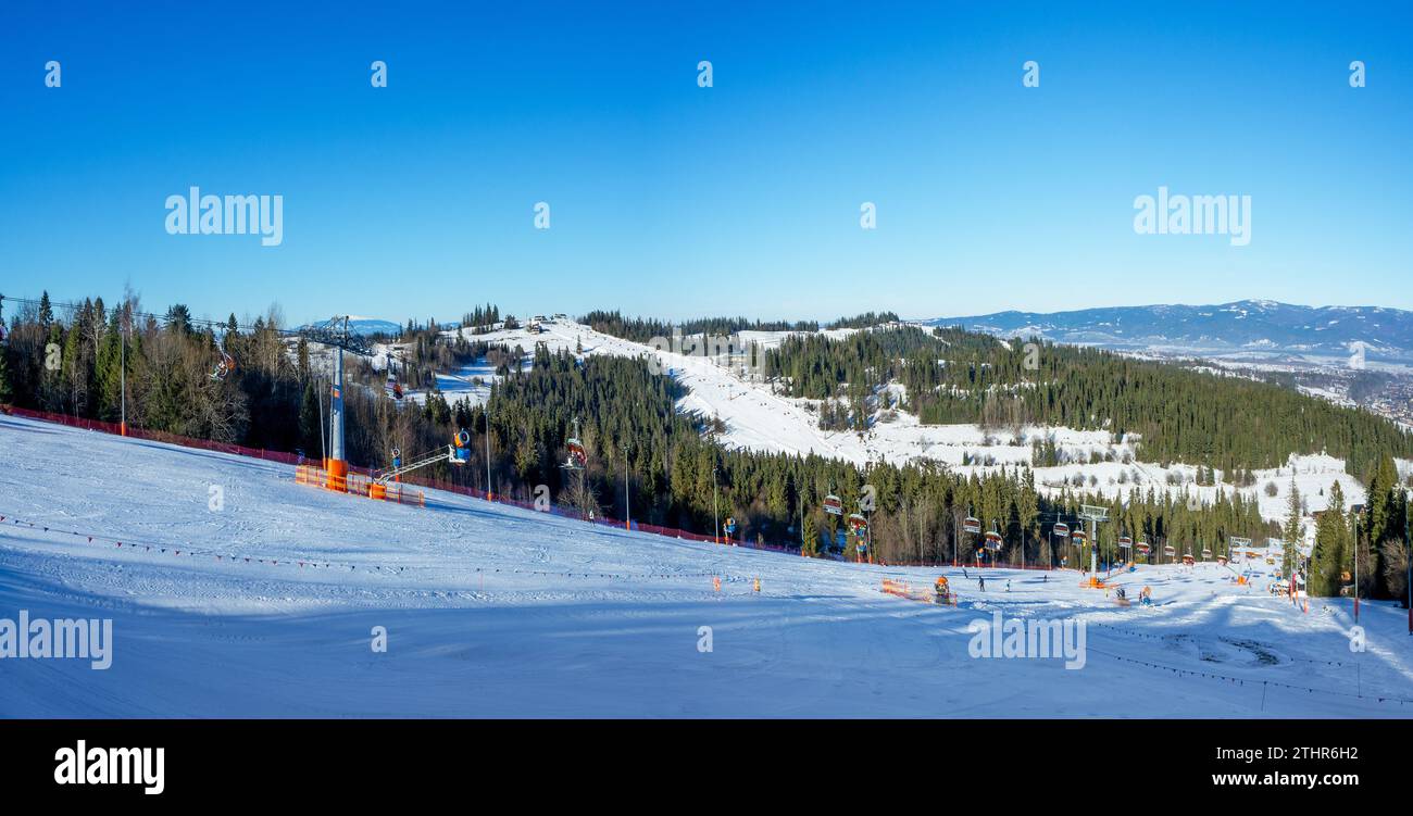 Skipisten, Sessellifte, Skifahrer und Snowboarder im Winter im Skigebiet Bialka Tatrzanska in Polen. Luftpanorama in tiefem Dezemberlicht mit blauen s Stockfoto