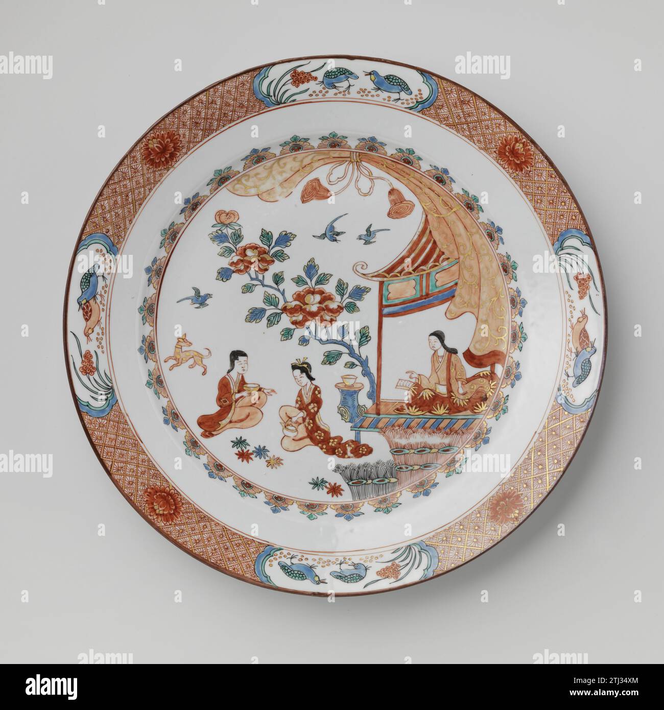 Schüssel mit drei Frauen in der Nähe eines Pavillons, anonym, ca. 1700 - ca. 1724 Porzellanschale, auf der Glasur in Blau, Rot, Grün, Schwarz und Gold gemalt. Auf der Wohnung zwei Teetrinker und ein Hund in einem Garten bei einem Pavillon und Pavillon; Eine dritte Frau ist im Pavillon; der Rand der Wohnung mit einem gebundenen Vorhang; an der Wand ein Reifen mit halbem Blumenhalm; der Rand mit Servierwerk mit Chrysanthemen durchsetzt mit vier gelappten Kartuschen mit Wachtel. In Europa im japanischen Imari-Stil eingerichtet. Chinapainter: Porzellan Europa. Glasur. Gold (Metall) Malerei / Vergoldung / Glasur Porzellan Stockfoto