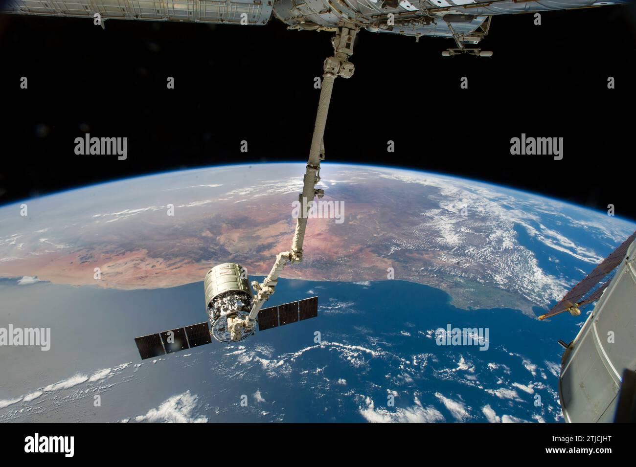 Die Canadarm2 der Internationalen Raumstation bereitet sich darauf vor, das Frachtschiff der Orbital Science Corporation freizugeben, nachdem sie einen Monat lang den Außenposten besucht hat. ESA-Astronaut Alexander Gerst und NASA-Astronaut Reid Wiseman, beide Flugingenieure der Expedition 40, befanden sich an der Steuerung der Robotik-Workstation in der Cupola, um Cygnus vom Harmony-Knoten zu entfernen und ihn sicher freizugeben. August 2014. Ein großer Teil Südafrikas bildet den Panoramahintergrund für die Szene, mit dem Kap der Guten Hoffnung unten rechts im Bild eine optimierte Version eines Originalbildes der NASA / Credit: NASA Stockfoto