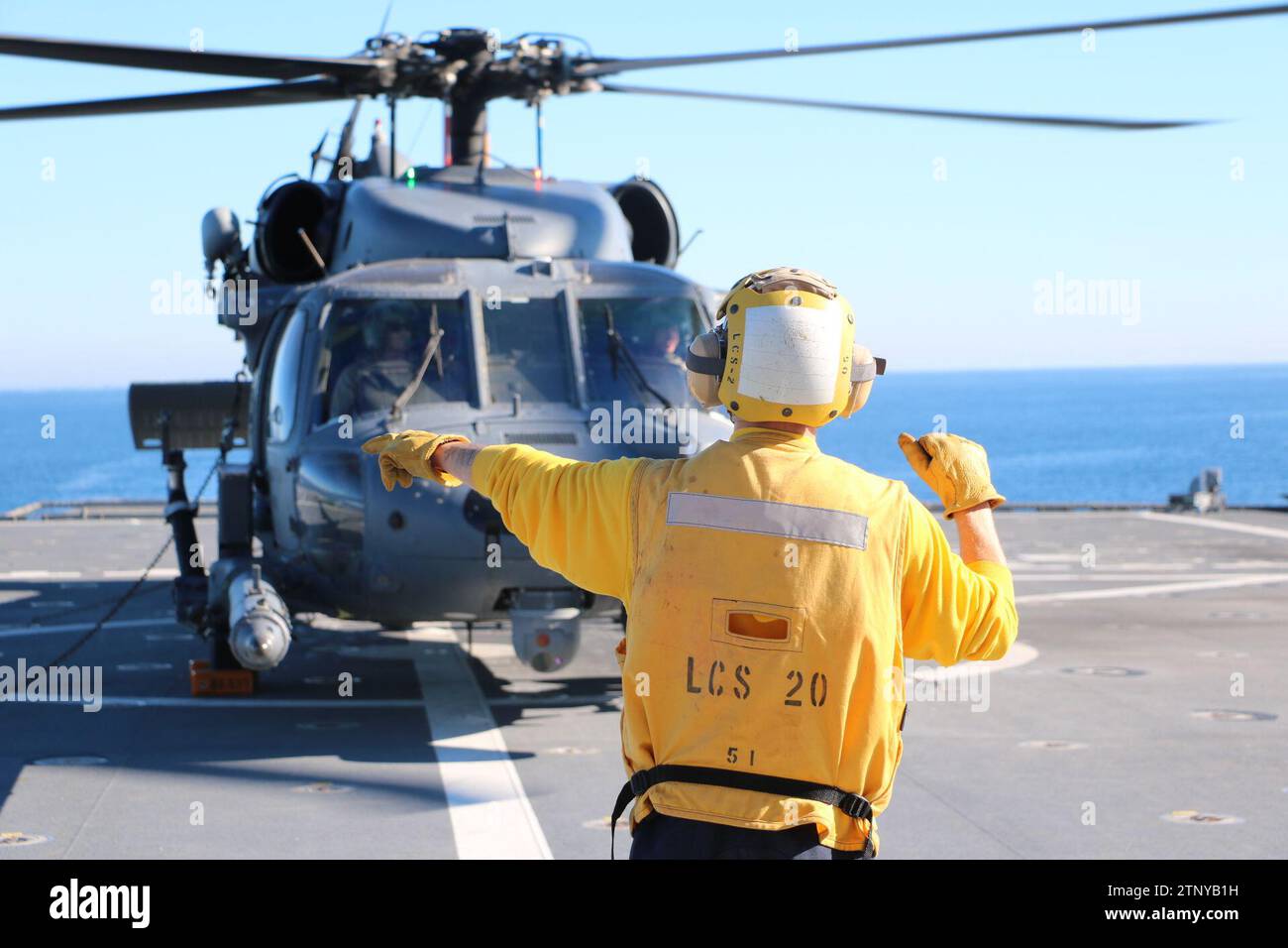 Die Mineman 3rd Class Ethan Crawford, gebürtig aus Edmore, Michigan, ist an Bord des Gefechtsschiffes der Independence-Variante USS Cincinnati (LCS 20), leitet einen HH-60G Pave Hawk Hubschrauber der Air Force, der der 305th Rescue Squadron, 943d Rescue Group, 920th Rescue Wing, zugewiesen ist. als er auf dem Flugdeck des Schiffes landet, um die Übung Steel Knight 23.2, 5. Dezember 2023, zu unterstützen. Steel Knight ist eine dreiphasige Übung, die die I Marine Expeditionary Force in der Planung, dem Einsatz und der Kontrolle einer gemeinsamen Truppe gegen eine Peer- oder Near-Peer-Gegner-Kampftruppe trainieren und bestehende Live-f verbessern soll Stockfoto