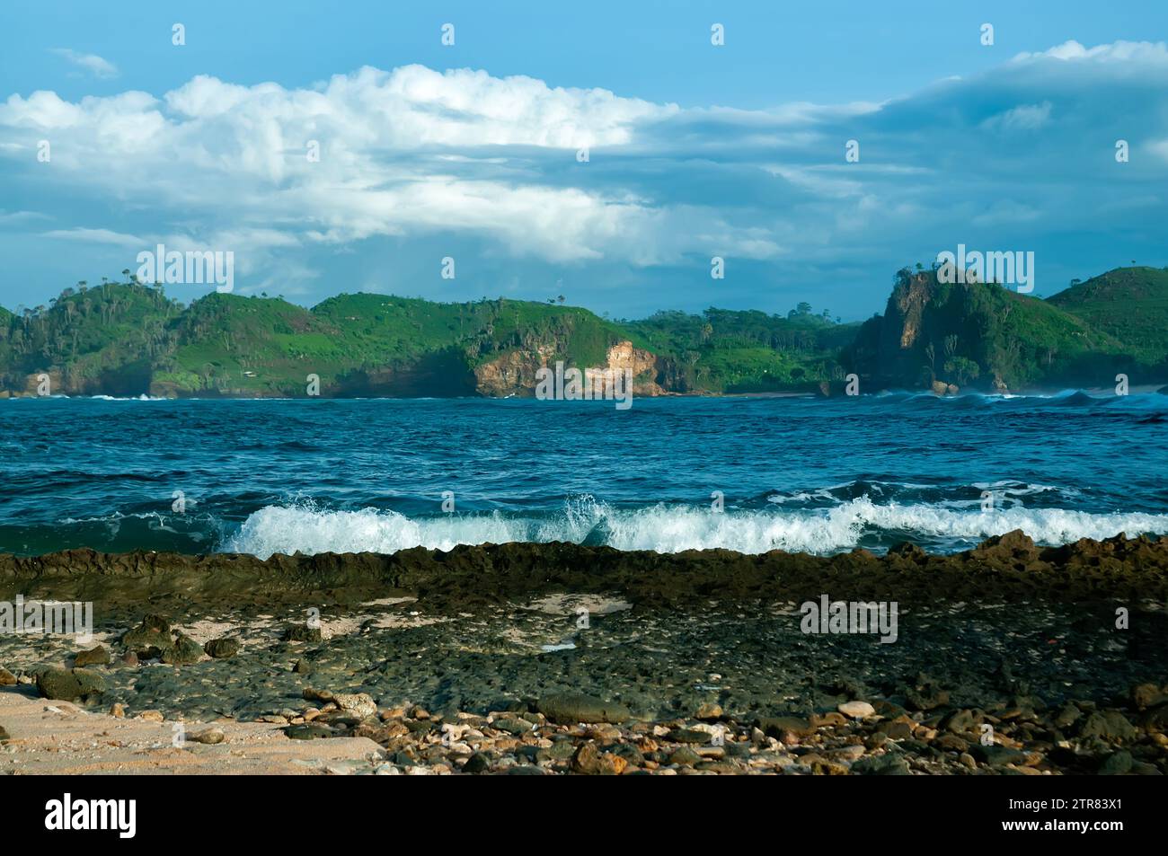 Sonnenaufgang am Bengkung Beach, Malang, Indonesien. Abstürzende Wellen, steile Felsen und blaue Wolken. Stockfoto