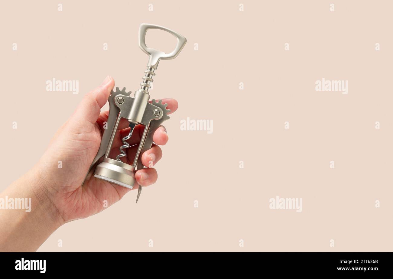 Männliche Hand, die Korkenzieher isoliert auf beigefarbenem Hintergrund hält. Stockfoto