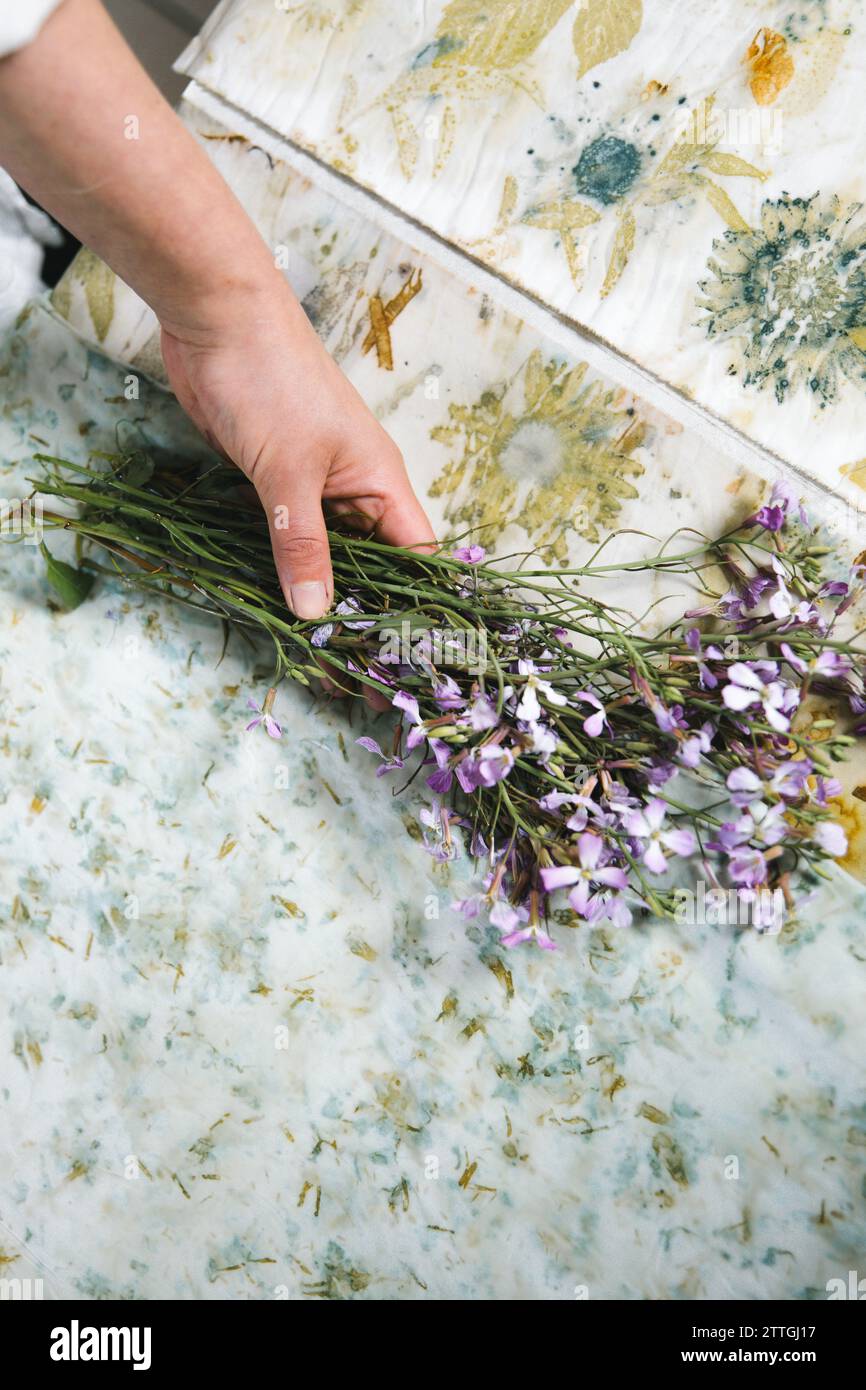 Textilkünstler, Blumenstrauß in der Hand. Stoff gefärbt mit natürlichen Blumenmustern. Botanisches Muster. Kopierbereich. Stockfoto