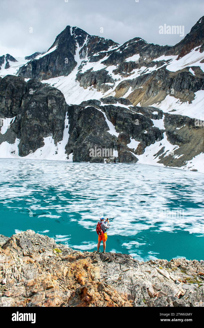 Ein einsamer Wanderer betrachtet die Weite des eisigen Wedgemount Lake. Stockfoto