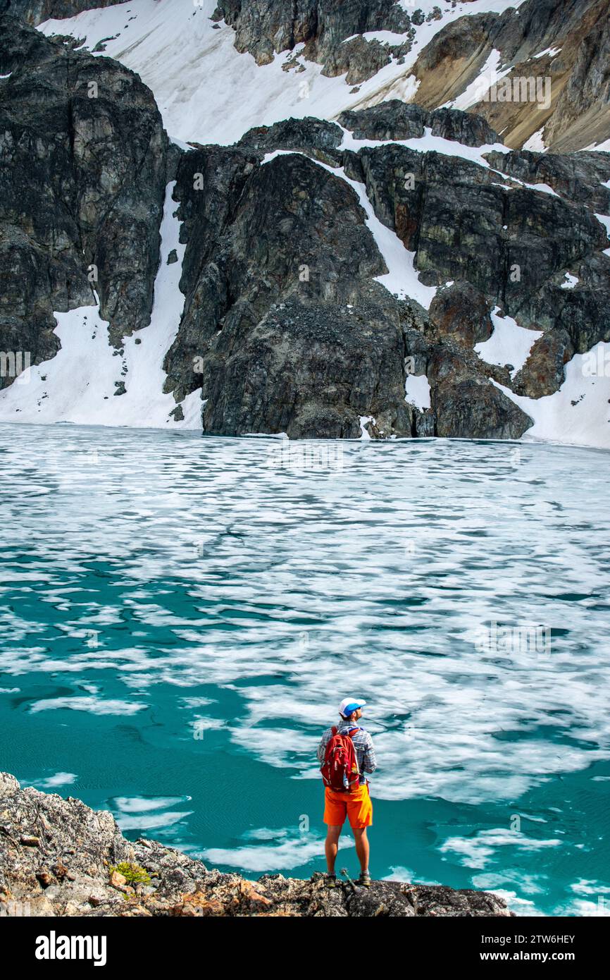 Ein einsamer Wanderer betrachtet die Weite des eisigen Wedgemount Lake. Stockfoto
