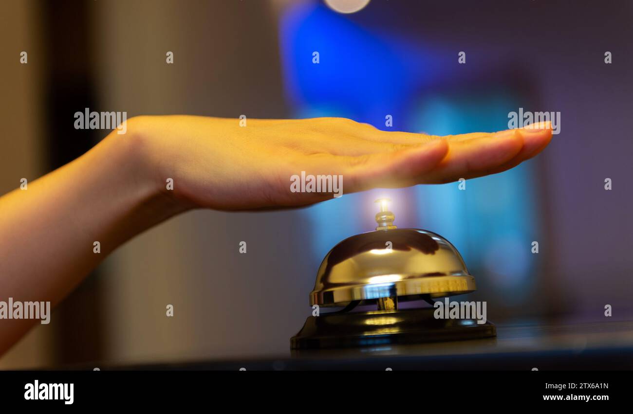 Weibliche Hand klingelt in der Serviceglocke auf Holztisch Stockfoto