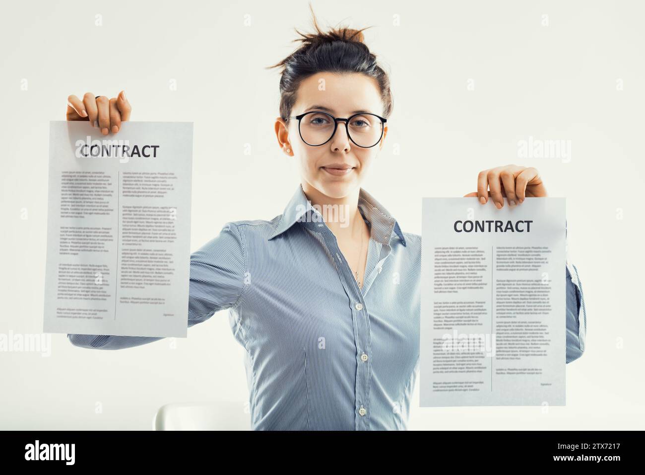 Ein Geschäftsmann präsentiert selbstbewusst zwei Verträge, was auf eine erfolgreiche Verhandlung oder Partnerschaft hinweist Stockfoto