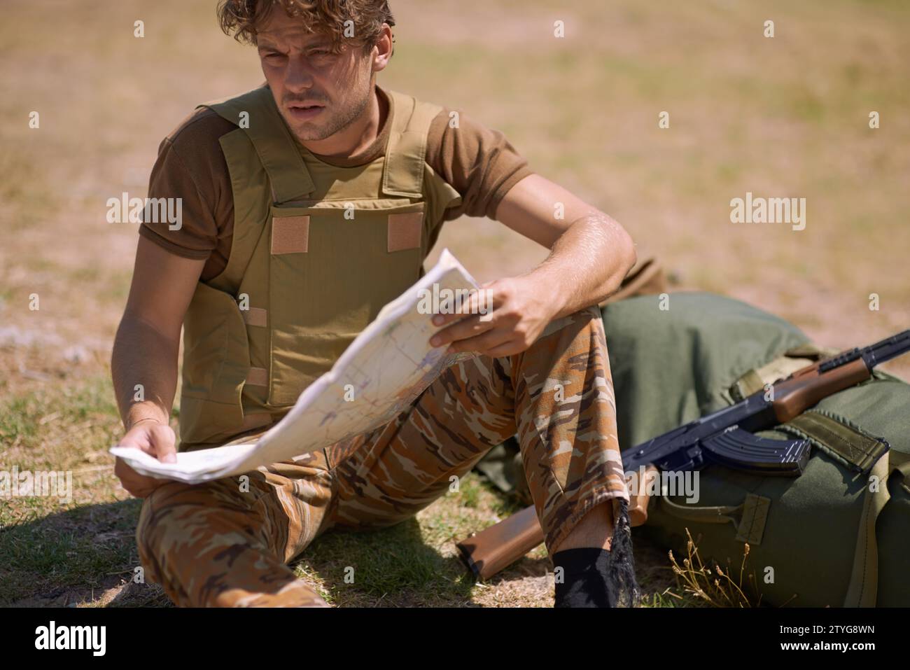 Soldat mit Landkarte im Freien, Planung der Kampfroute oder taktische Einsatzziele für Kriegsmissionen. Mann auf dem Schlachtfeld oder im Militärstützlager, überprüfen Sie Stockfoto