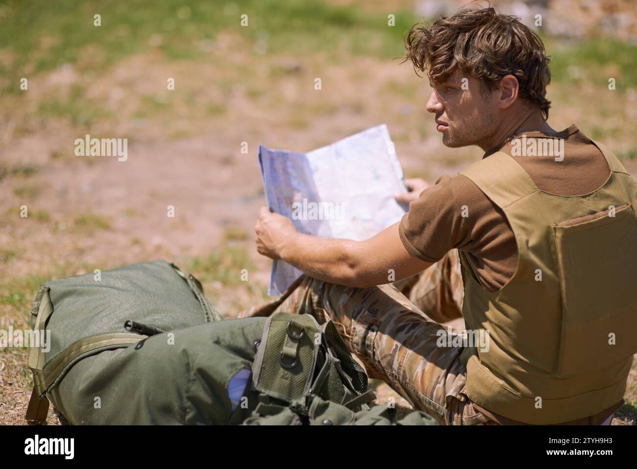 Soldat mit Karte auf dem Schlachtfeld, Planung des Schlachtortes oder taktische Einsatzziele für Kriegsmissionen. Der Mann ist draußen im Militärstützpunkt, Check Stockfoto